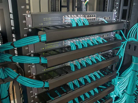 Rack de rede com switches e patch panels e os cabos organizados em feixes com guias