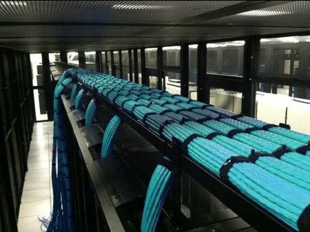 Data center com centenas de cabos de rede organizados em feixes sobre os racks